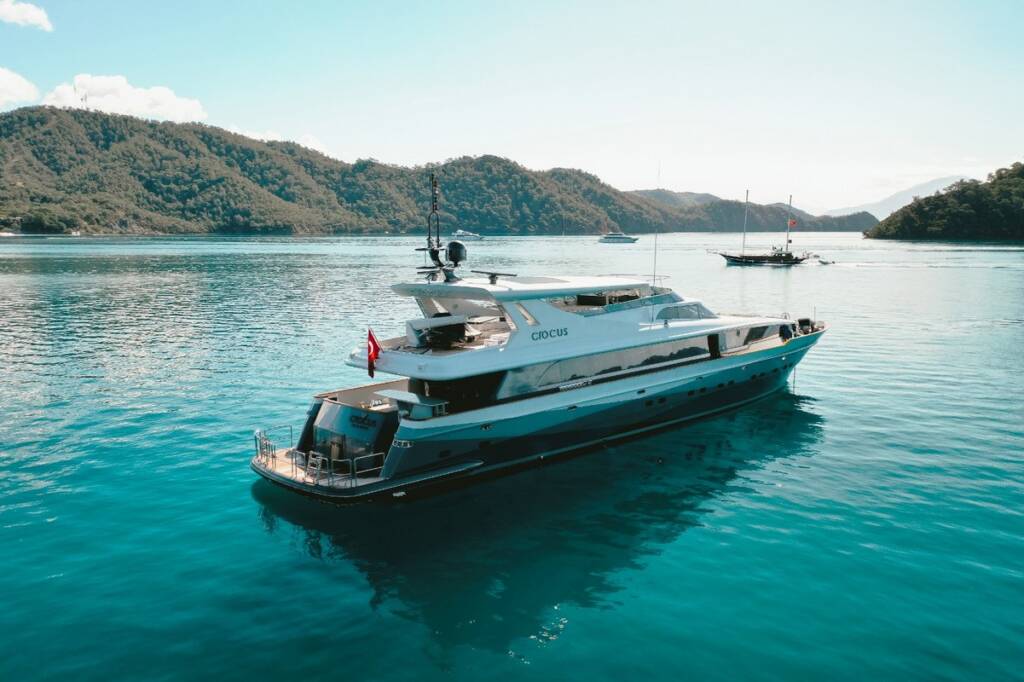 Luxury yacht Crocus, a beacon of elegance, anchors amidst traditional gulet yachts in Göcek Bay.