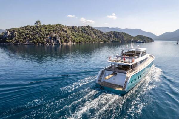 A luxurious yacht cruising across the deep blue waters of Turkey, with passengers relaxing on expansive decks and enjoying the stunning scenery.