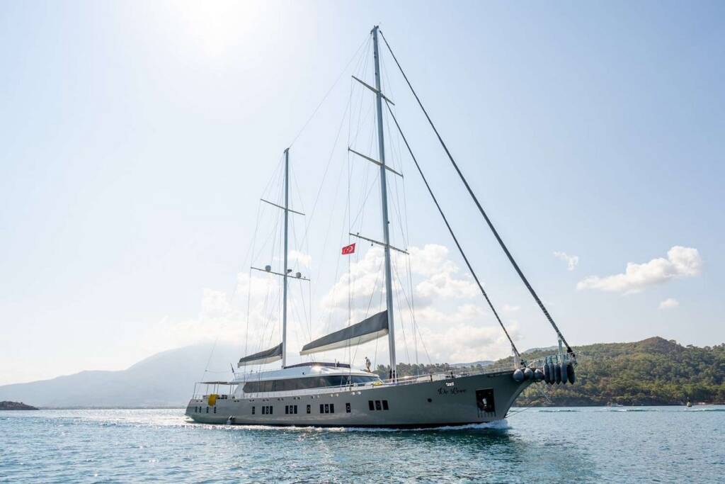 Motorsailer De Love anchored in the Mediterranean, showcasing its elegant design and spacious sun deck.