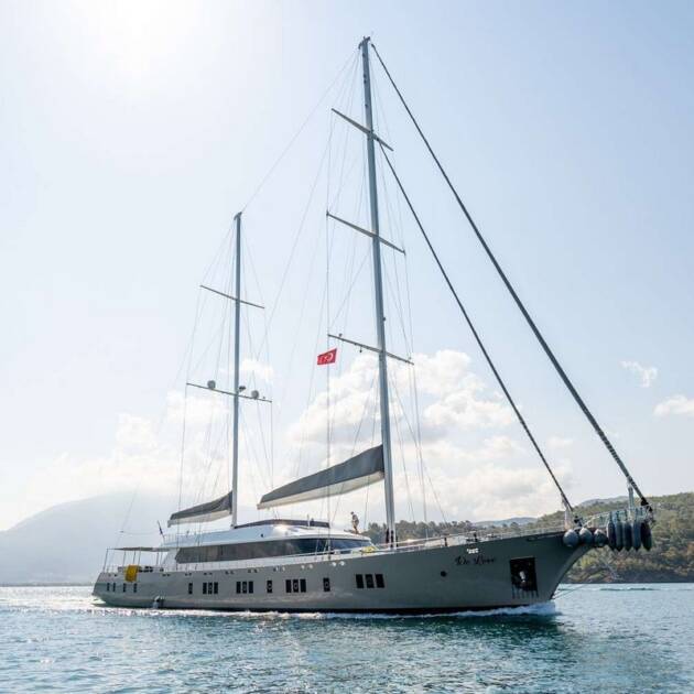 Motorsailer De Love anchored in the Mediterranean, showcasing its elegant design and spacious sun deck.